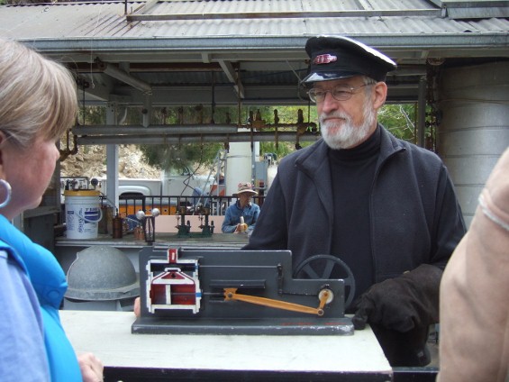 A docent demonstrates a model steam engine