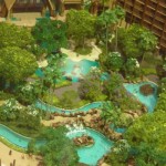 The pool area features lava rock slides, tube rivers, water play areas, and hidden pathways for families to enjoy